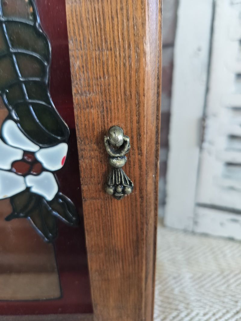 Close-up of French vintage wooden spice cabinet with stained glass floral front and decorative metal handle