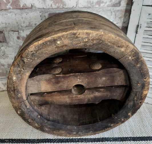 Antique French wooden pulley wheel with rustic aged wood and iron bolts, vintage farmhouse decor piece.