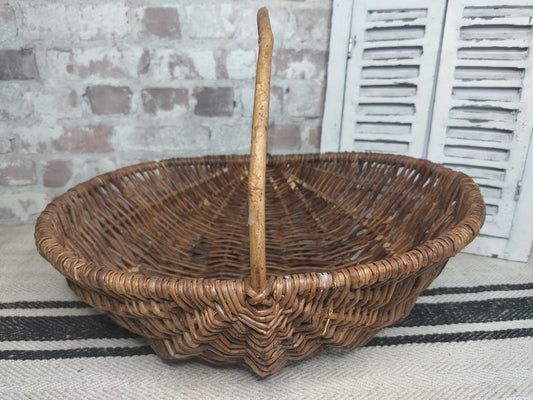 Vintage French wicker basket with woven willow and central handle in rustic brown tones